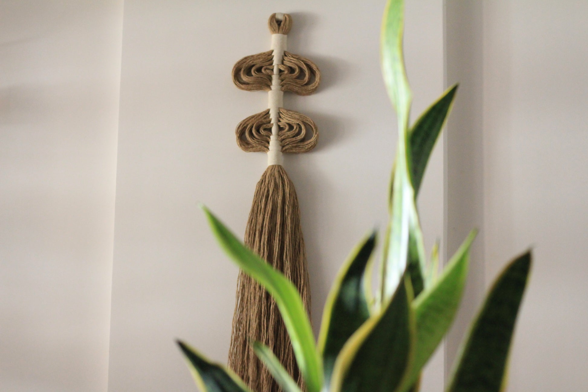 Organic and textural handwrapped jute wall art, showcasing intricate patterns and natural hues, adding a rustic and contemporary feel to the room