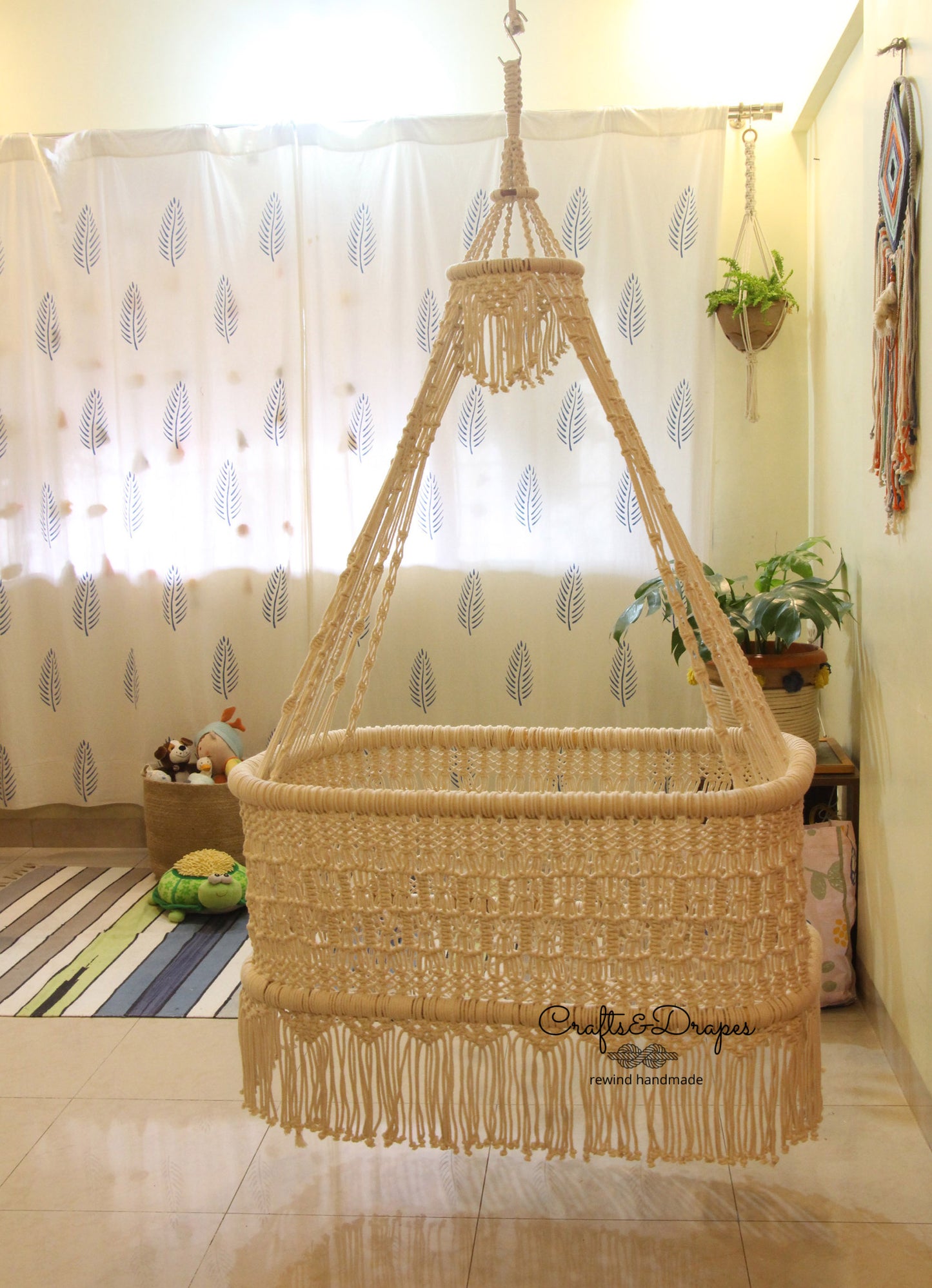 Boho-inspired macramé baby cradle, intricately woven with soft, sustainable cotton cords, and a sturdy wooden cane frame