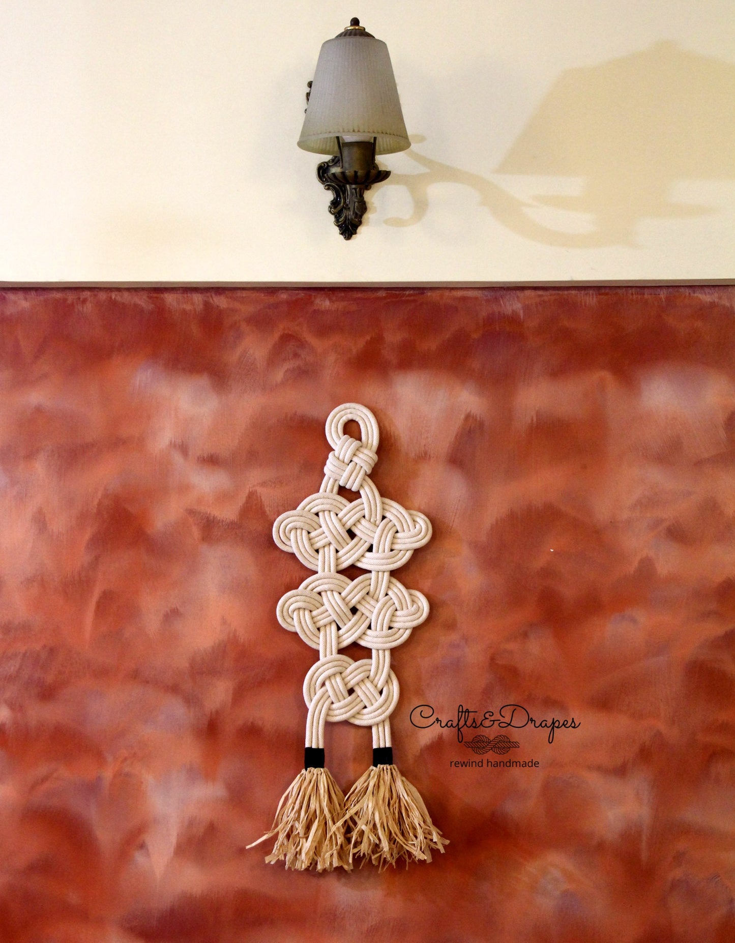 Celtic knot rope wall art with intricate design and raffia fringe, combining cultural heritage and natural textures to create a captivating and elegant decorative piece.