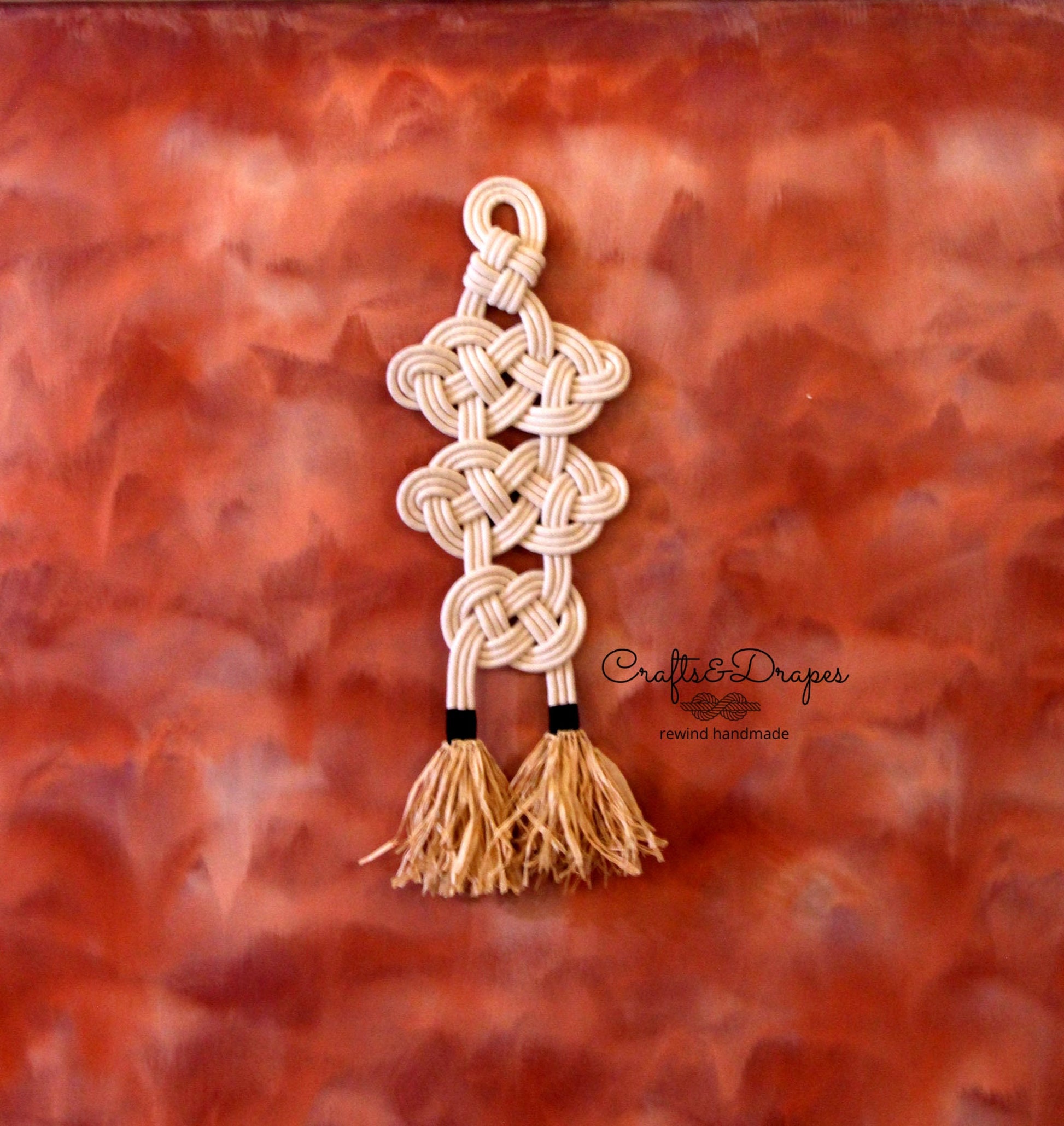 Celtic knot rope wall art with intricate design and raffia fringe, combining cultural heritage and natural textures to create a captivating and elegant decorative piece.